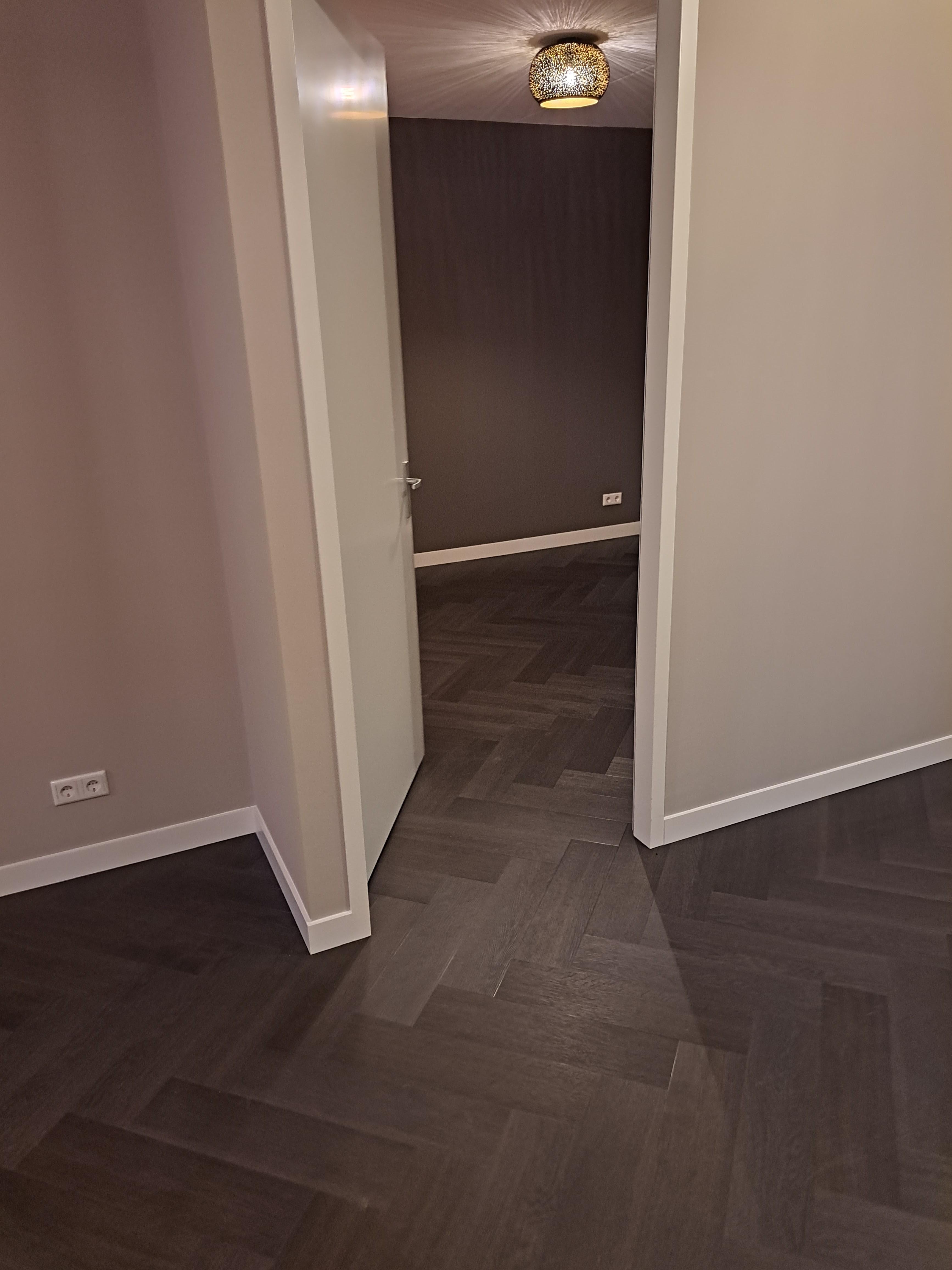 Donkere visgraatvloer in een kamer met een accentwand