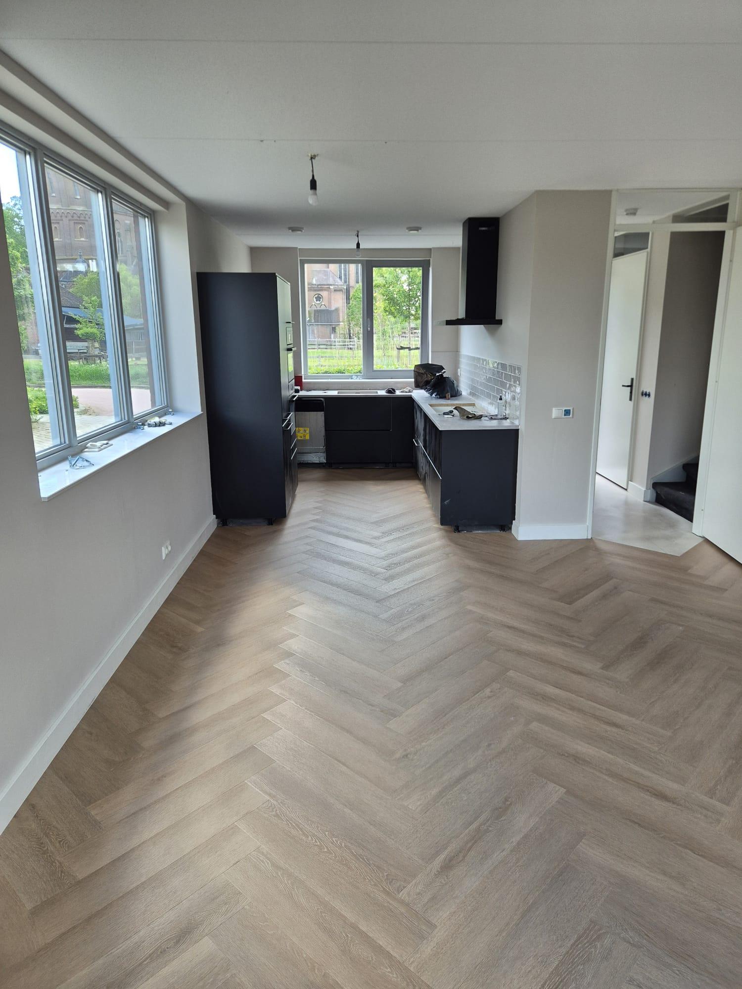 Visgraatvloer in een open woonkamer met keuken