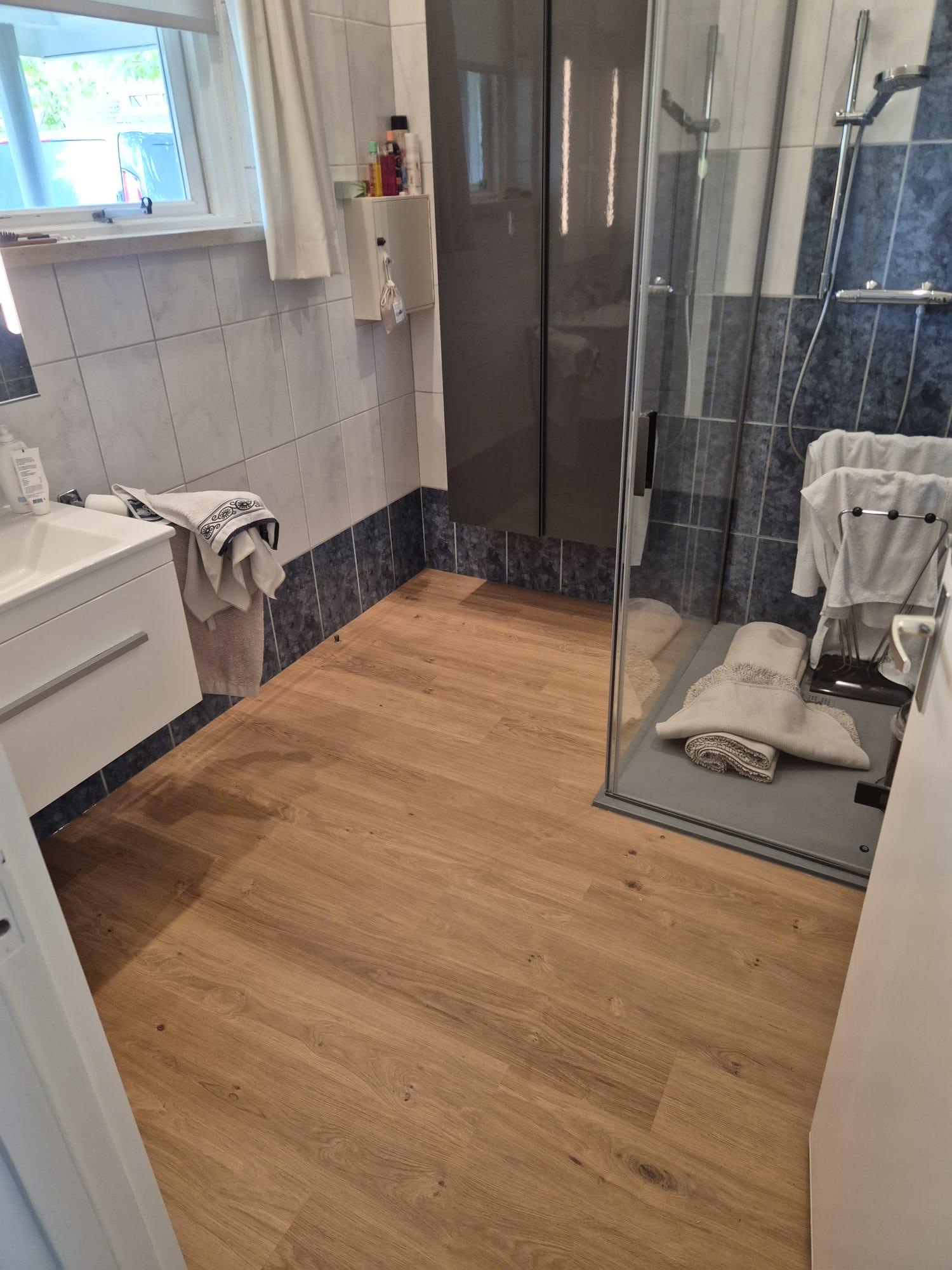 Houtlook plak-pvc in rechte planken in een badkamer en overloop